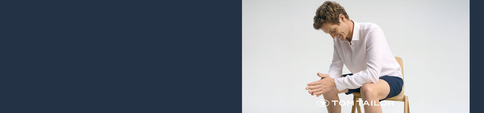 Mann sitzt entspannt am steinigen Meeresufer