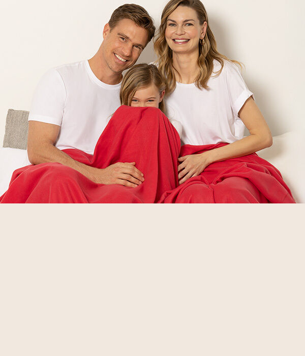 Familie sitzt gemeinsam unter roter Decke